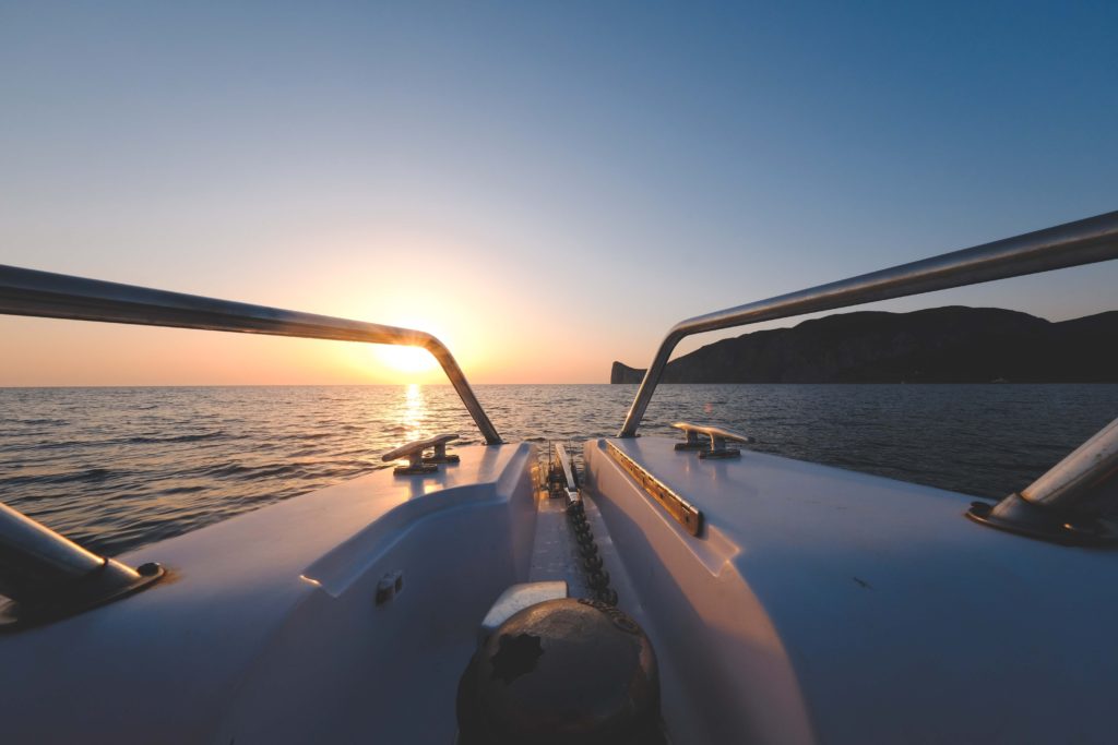 View from the cockpit of a yacht towards the ocean, a mountain and sunset